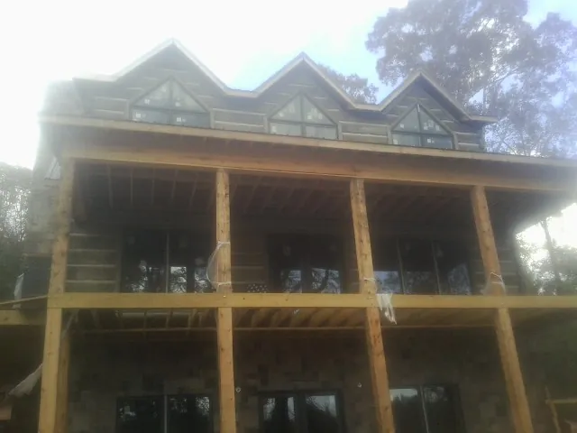 Dormers and porch framing on a large log home under construction — Roof Coating work by our crew in Waterville